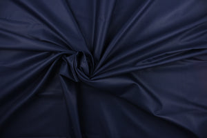 This beautiful solid navy blue fabric has a smooth and lustrous appearance.  The fabric offers a crisp hand and a stiff but flexible drape.  The glossy finish makes it great for apparel, drapery lining and much more.   