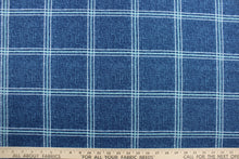 Load image into Gallery viewer, This solarium outdoor print features a plaid design with white and blue green stripes against a denim blue background.  It is durable and can withstand up to 500 hours of sunlight, water and stain resistant and has 10,000 double rubs.  It is perfect for cushions, tablecloths, decorative pillows and upholstery projects.  Bring indoors when not in use.  We offer this fabric in other colors.
