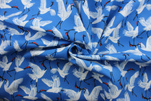 Load image into Gallery viewer, Black Cranes is a printed polyester outdoor fabric featuring a beautiful, bold cobalt blue background with white and black cranes.  The fabric is fade resistant, water repellant and provides up to 33,000 double rubs of wear-resistance, making it ideal for outdoor furniture and accessories.  Uses include cushions, tablecloths, upholstery projects, decorative pillows and craft projects. 
