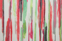 Load image into Gallery viewer, All Lined Up is an outdoor fabric that features a bold, vibrant, and multi-colored abstract line design. Made up of shades of coral, green, white, and grey with hints of pink, the fabric is a sustainable solution due to its 33,000 double rubs. Perfect for those looking to make a statement in their outdoor space. Uses include cushions, tablecloths, upholstery projects, decorative pillows and craft projects. 
