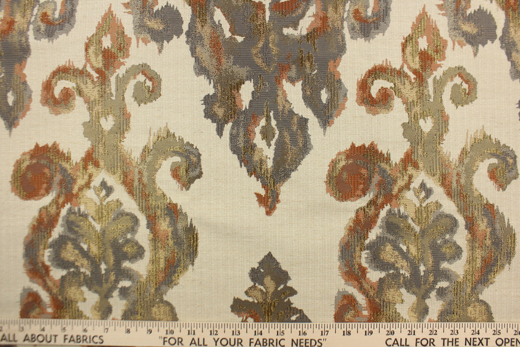  This fabric features a watercolor demask design in orange, coral, gray, gold and beige against a pale beige. 