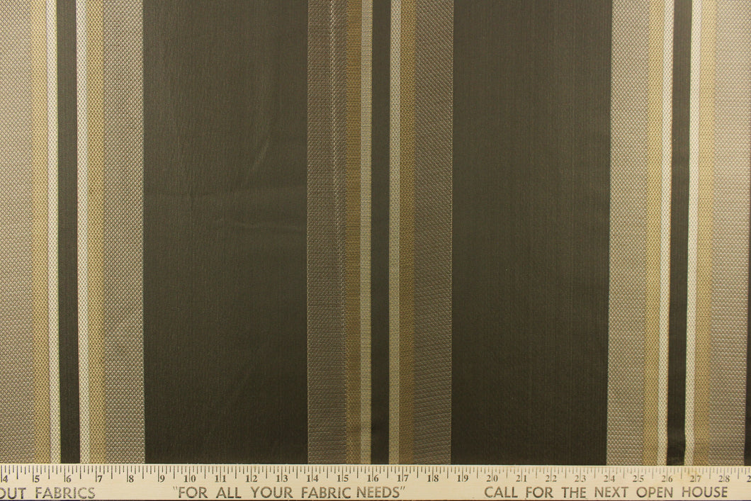 This rich woven yarn dyed fabric features bold multi width striped pattern in shades of pewter and gold on a dark brown background. 