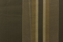 Load image into Gallery viewer, This rich woven yarn dyed fabric features bold multi width striped pattern in shades of pewter and gold on a dark brown background. 
