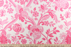 This fabric features a  large floral vine design with  colors in varying shades of pink flowers on a white background.