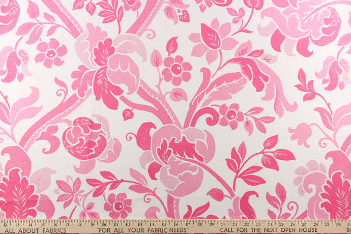 This fabric features a  large floral vine design with  colors in varying shades of pink flowers on a white background.