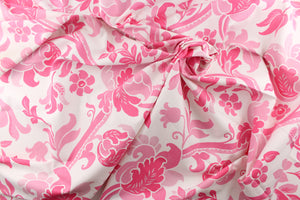 This fabric features a  large floral vine design with  colors in varying shades of pink flowers on a white background. 