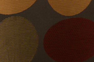 Stylish, modern and contemporary best describe this geometric pattern of circles and ovals in red, gold and brown on a dark brown background .