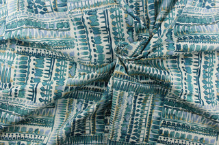 : This fabric has a geometric look with squares full of  rows of what looks like paint blots, in different tones of turquoise with hints of water blue and khaki set against a dull white. 