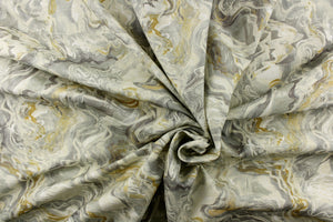  This fabric features a marble look in gray tones, mute gold, white and off white. 