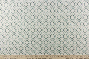 This fabric features a geometric design in a gray green and blue against a white background. 