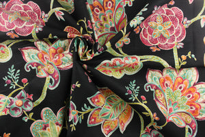  A dramatic fabric with bold colors featuring a large floral print has a black background with teal green, orange, purple, hints of beige and white, and dark pink or burgundy colors.