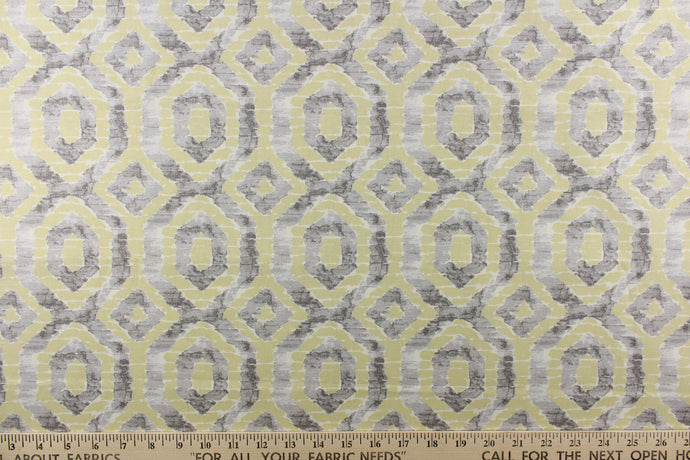 This beautiful fabric features a geometric design in gray and a pale yellowish green color with hints of white.