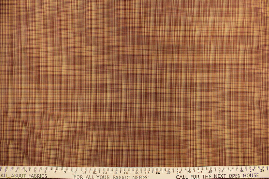 This stunning yarn dyed fabric features a small plaid design in a deep red and golden tan. 
